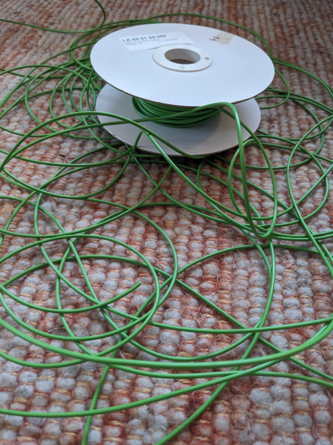 Green wire spread across a carpet.